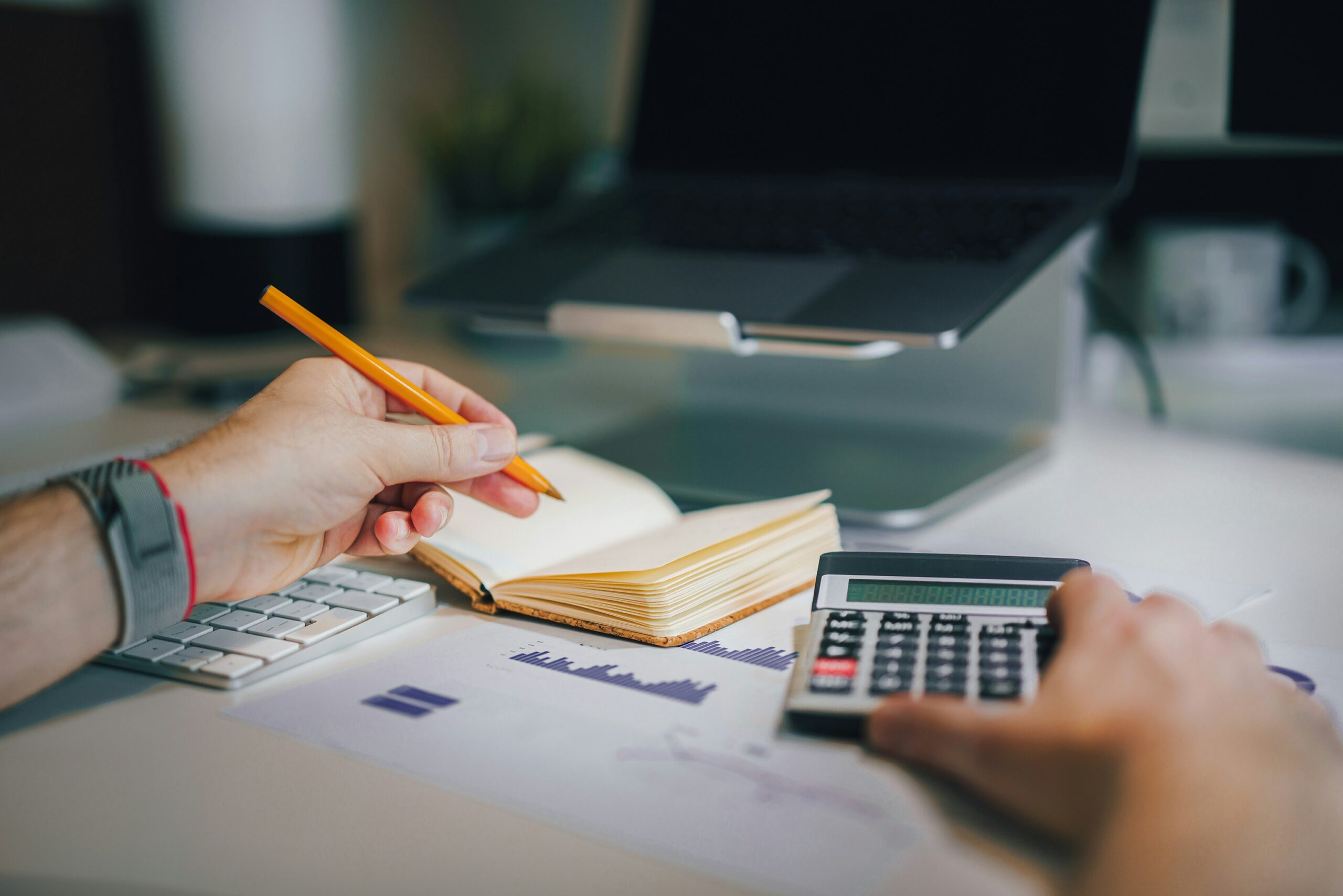 Personne analysant ses dépenses mensuelles avec un ordinateur et une calculatrice