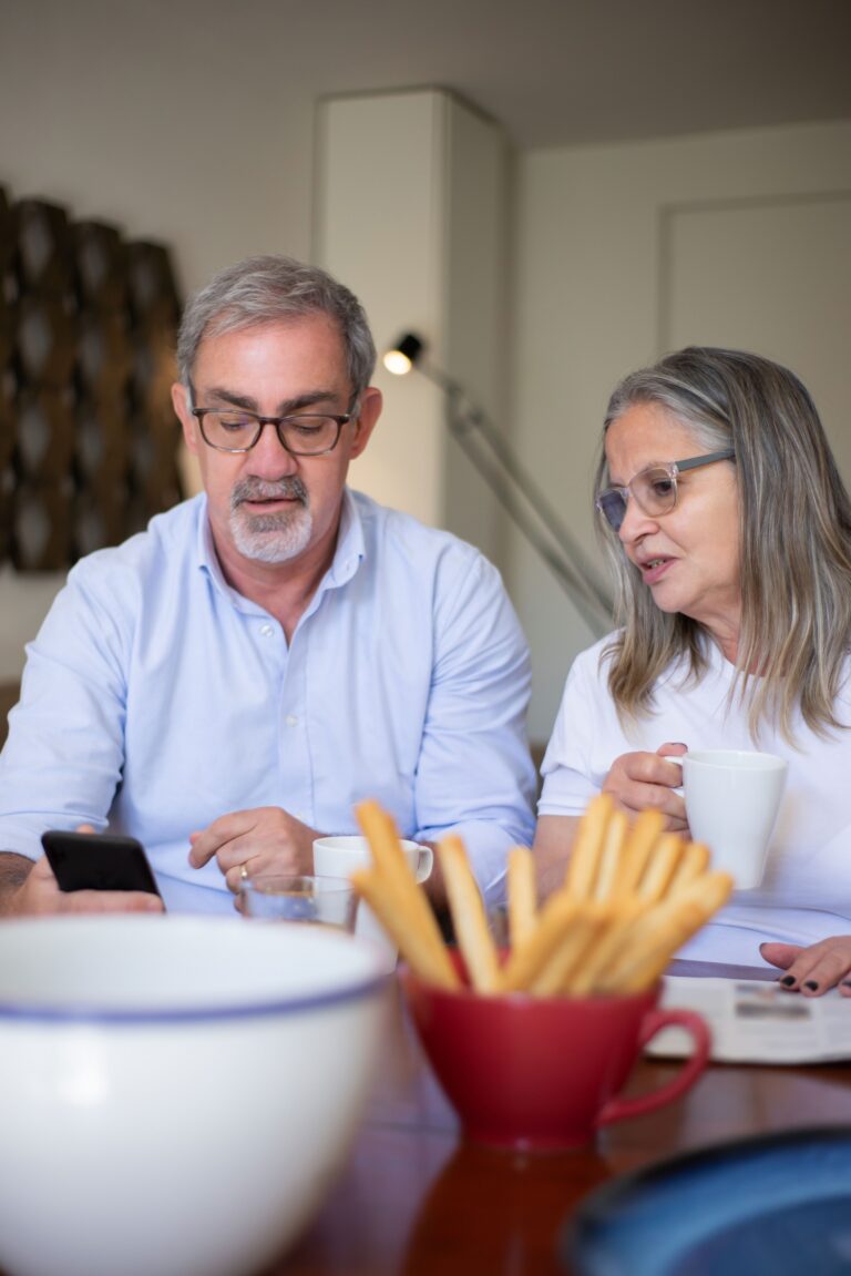 Parent de plus de 50 ans discutant avec son enfant adulte autour d’un budget familial et d’une calculatrice