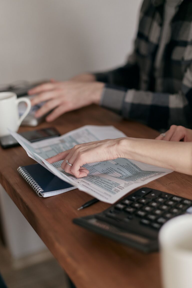 Couple de plus de 50 ans faisant un bilan financier annuel avec documents, calendrier, carnet de budget et calculatrice