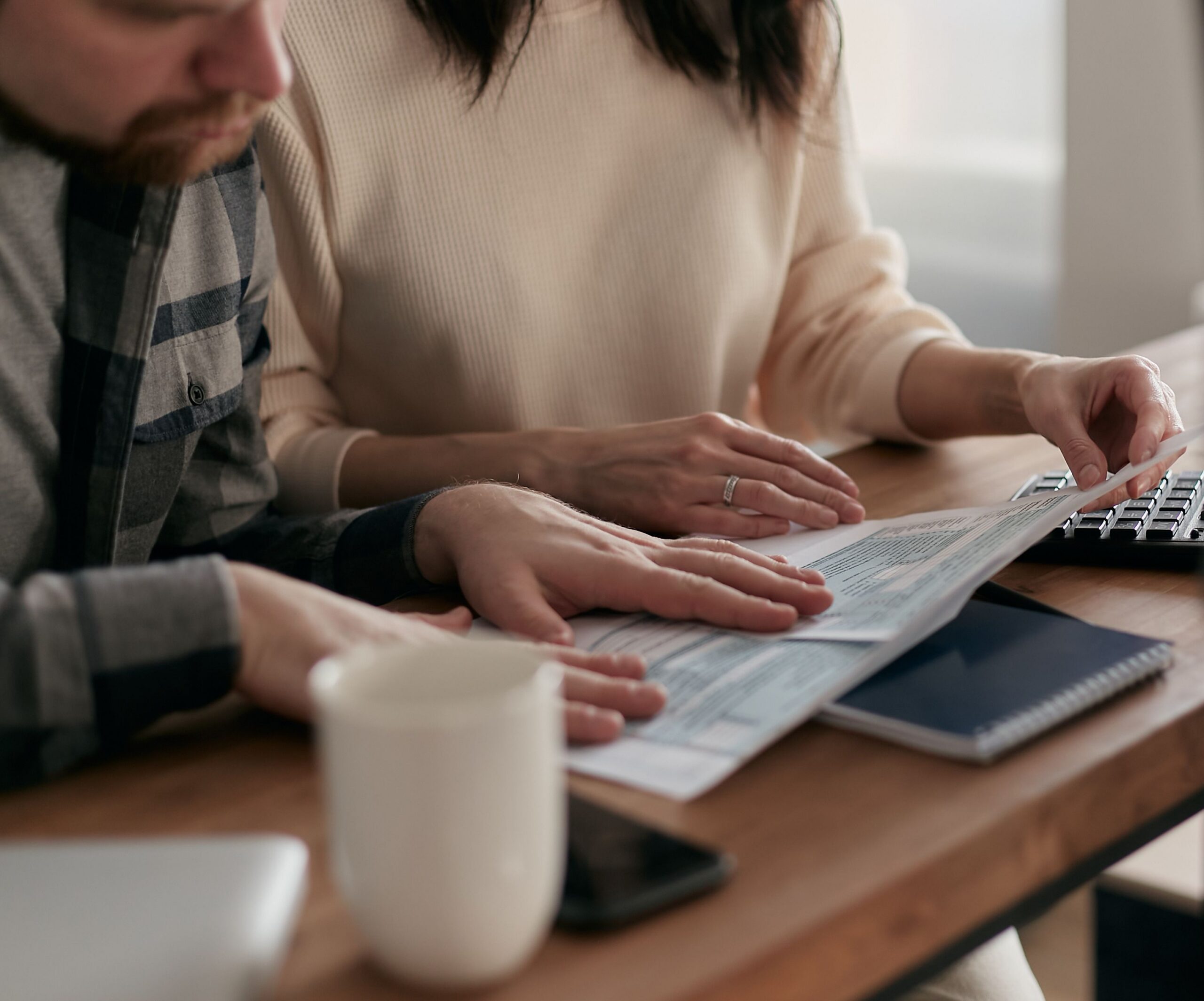 Couple de plus de 50 ans faisant le point sur son budget avec des factures, un carnet et une calculatrice
