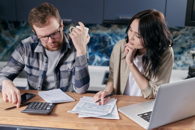 Couple de plus de 50 ans préparant son budget santé avec des documents, une calculatrice et un carnet
