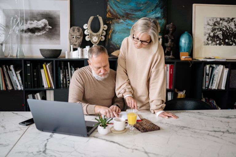 Couple de plus de 50 ans organisant ses documents importants avec des dossiers, contrats, carnet de budget et calculatrice