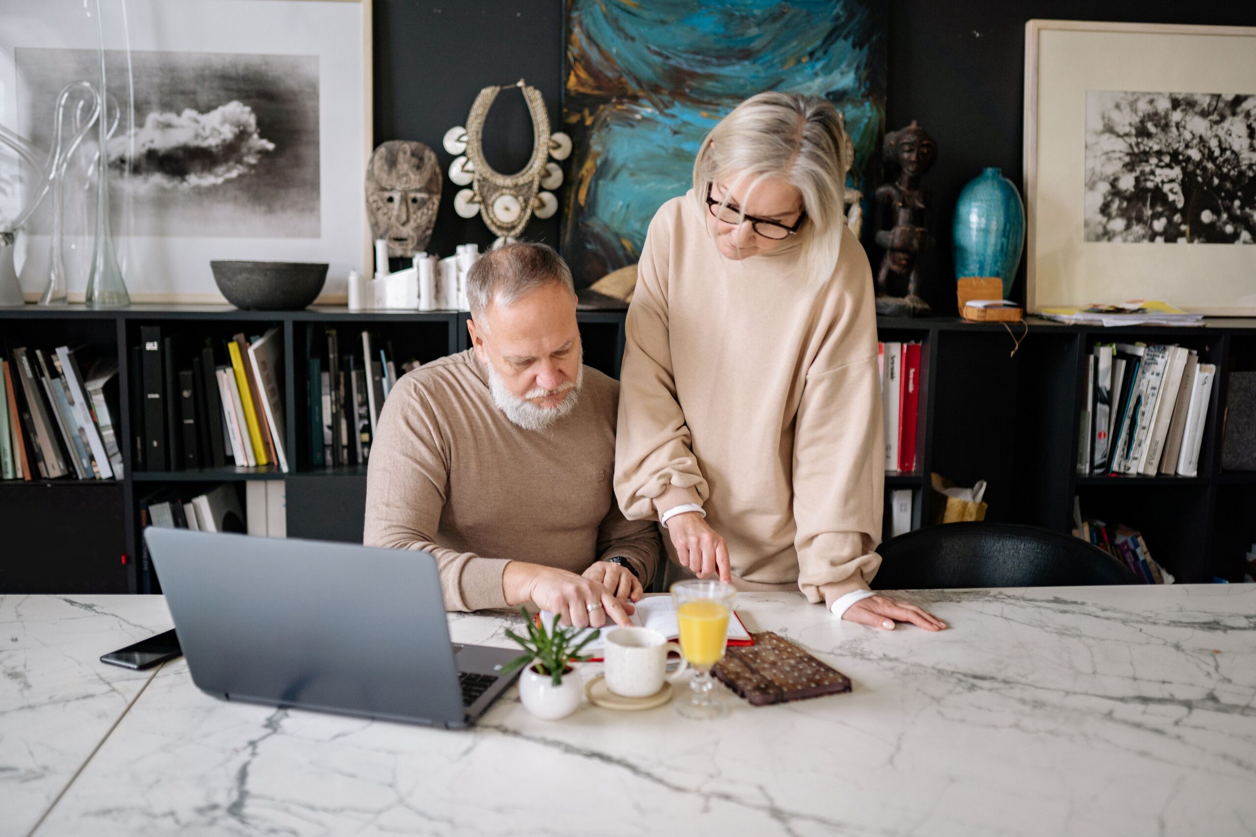 Couple de plus de 50 ans organisant ses documents importants avec des dossiers, contrats, carnet de budget et calculatrice